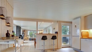 A modern kitchen with wooden flooring, a central island, and two bar stools.