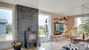 A modern living room with a stone fireplace, a television, and a cozy seating area.