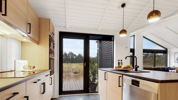 A modern kitchen with wooden cabinets, a central island, and a view to the outdoors.