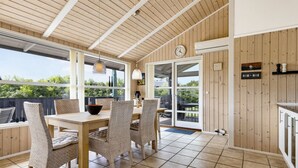 A dining area with a wooden table and chairs, a clock, and a view of the outdoors.