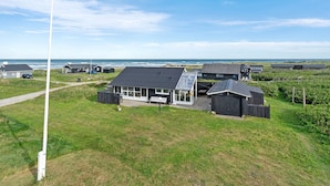 A coastal property with multiple buildings, including a main house with a large patio and a smaller structure with a sloped roof.