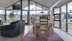 Une pièce spacieuse avec une grande table à manger, des chaises en bois, un canapé en cuir et un tapis rouge à motifs.