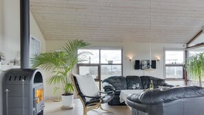 Un salon moderne avec une cheminée, des canapés en cuir, un fauteuil à bascule et de grandes fenêtres.