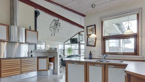 Une cuisine moderne avec des meubles en bois, une hotte de cuisine en acier inoxydable et une grande fenêtre qui laisse entrer la lumière naturelle.