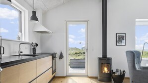 Eine moderne Küche mit großem Fenster, Einbauherd und Essbereich mit Tisch und Stuhl.