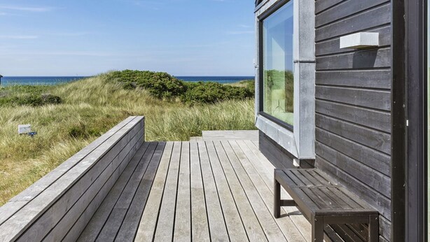 Eine Holzterrasse mit Bänken, die auf einen Strand und den Ozean blickt.