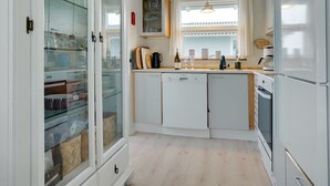 A modern kitchen with white cabinets, a built-in oven, and a glass-fronted display cabinet. - "Stavros" - 410m from the sea by Interhome (Hjørring)