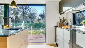 Una cuina moderna amb una illa gran, electrodomèstics integrats i vistes a l'exterior.