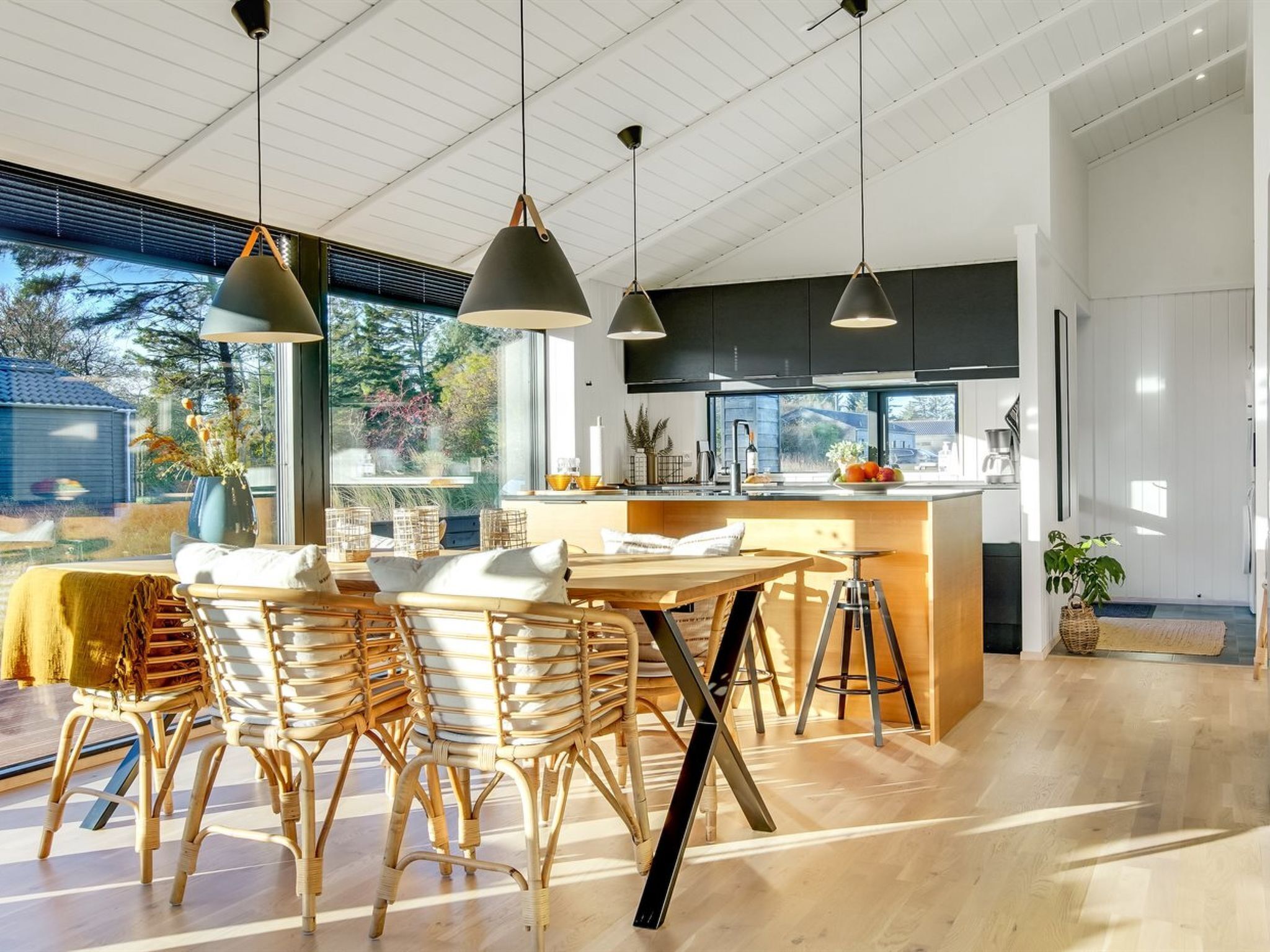Cocina moderna con una isla central, sillas de madera e iluminación colgante.