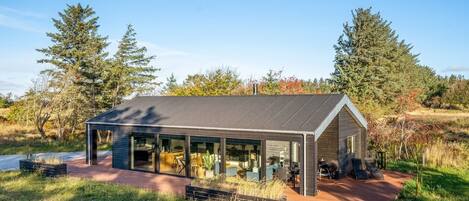 A modern house with a large glass extension, surrounded by a natural landscape.
