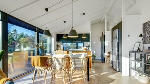 Una cuina moderna amb una illa gran, il·luminació penjant i vistes a l'exterior.
