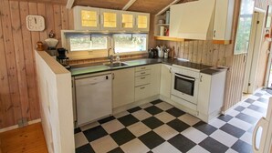 A compact kitchen with wooden walls, a black and white checkered floor, and basic amenities. - "Nakke" - 1.3km from the sea by Interhome (Hjørring)