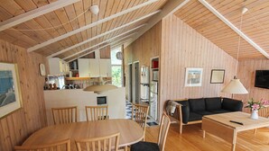 A cozy, wooden-floored living room with a dining area, a sofa, and a TV mounted on the wall. - "Nakke" - 1.3km from the sea by Interhome (Hjørring)