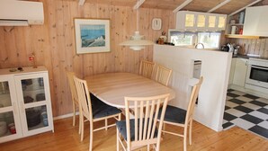A wooden interior with a dining table, chairs, a kitchen area, and a clock on the wall. - "Nakke" - 1.3km from the sea by Interhome (Hjørring)