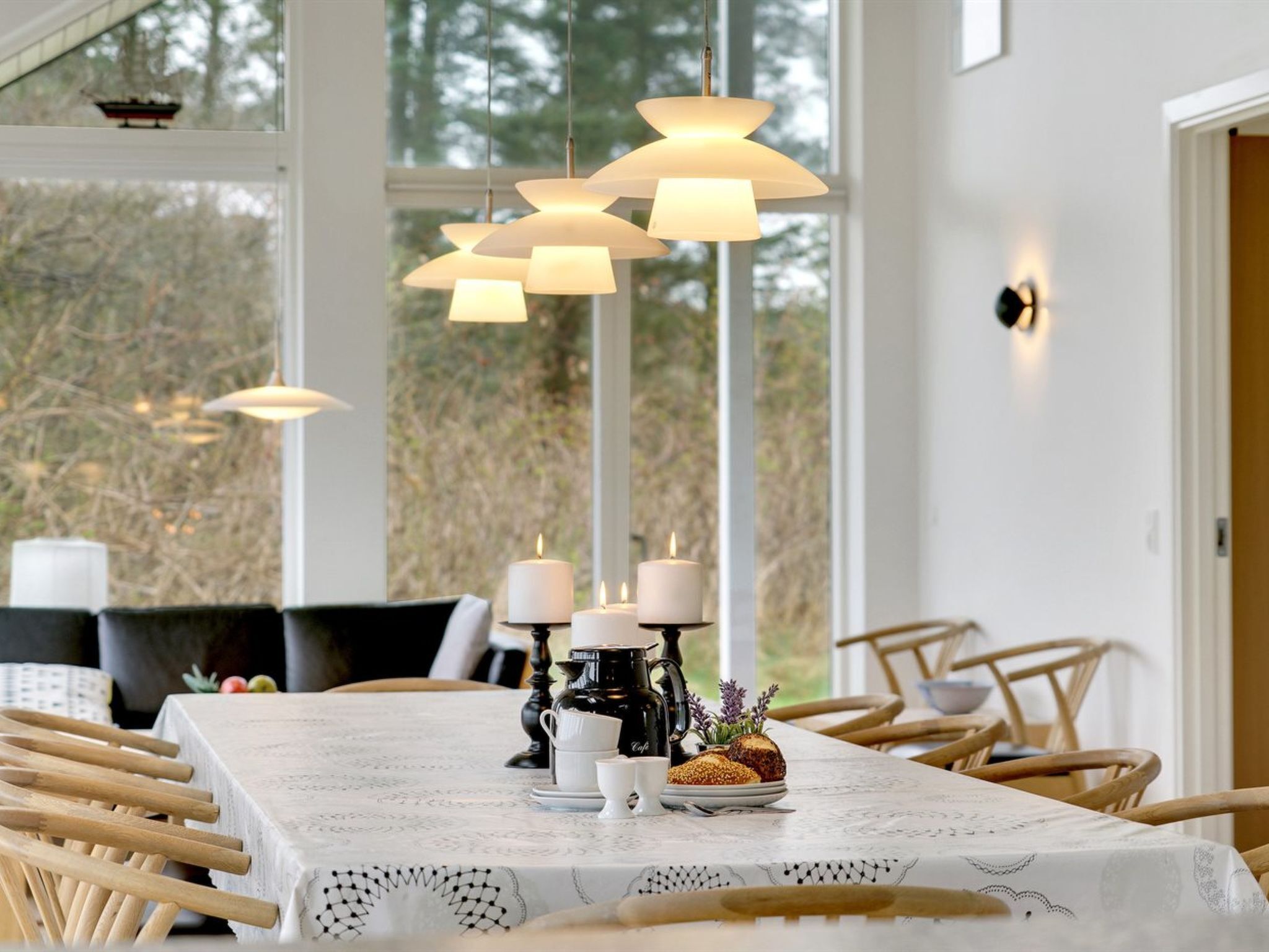 Comedor con una mesa dispuesta para cuatro personas, que incluye un mantel blanco, sillas de madera y un centro de mesa con velas.