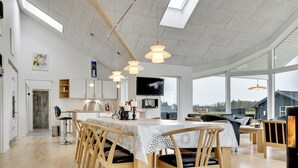Et rummeligt, moderne køkken med spiseplads, store vinduer og udsigt til det fri.