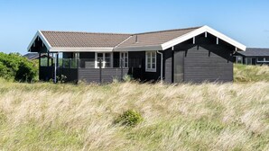 A modern house with a sloped roof, large windows, and a covered porch.