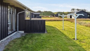 Un bâtiment moderne à l’extérieur sombre, doté de grandes fenêtres et entouré d’une cour verdoyante.