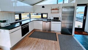 Une cuisine moderne avec des meubles blancs, des appareils en acier inoxydable et une grande fenêtre donnant sur un paysage magnifique.