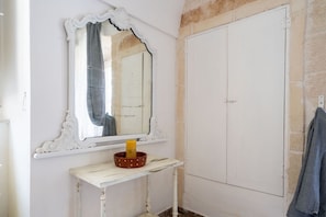 A white vanity with a mirror, a small table, and a white wardrobe.