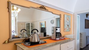 A kitchen with a large mirror, a kettle, a coffee maker, and a toaster on the counter. - GuestHost - Comfortable apartment that hosts 2 people, located in an old farmhouse dating back to the 19th century, furnished with taste and meticulous recovery of the original materials. The accommodation is located in Cozzana, a quiet and verdant distr (Monopoli)