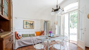 A room with a bed, a round table with chairs, a chandelier, and a door leading outside. - GuestHost - Nice apartment that hosts up to 2 people, located in an old farmhouse dating back to the 19th century, furnished with taste and meticulous recovery of the original materials. The accommodation is located in Cozzana, a quiet and verdant distri (Monopoli)
