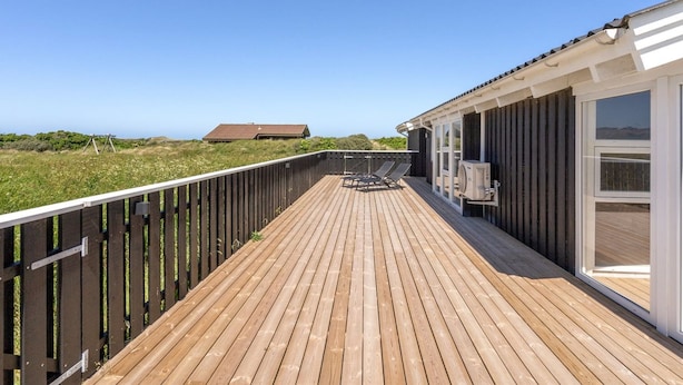 A wooden deck with a view of the beach and a building with large windows.