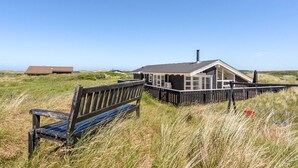 A wooden bench in a grassy field with a building in the background.