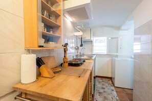 Une cuisine compacte dotée d’un plan de travail en bois, d’un porte-rouleau d’essuie-tout, d’un bloc à couteaux et d’un égouttoir.