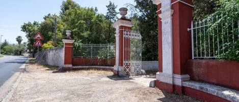 A gated entrance with a metal gate and a red wall.