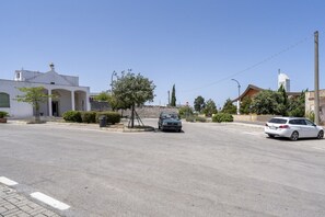Une rue avec un immeuble blanc, un arbre et des voitures garées.