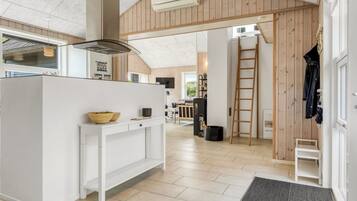 Une cuisine moderne dotée d’un îlot central, de murs recouverts de panneaux en bois et offrant une vue sur l’espace repas.