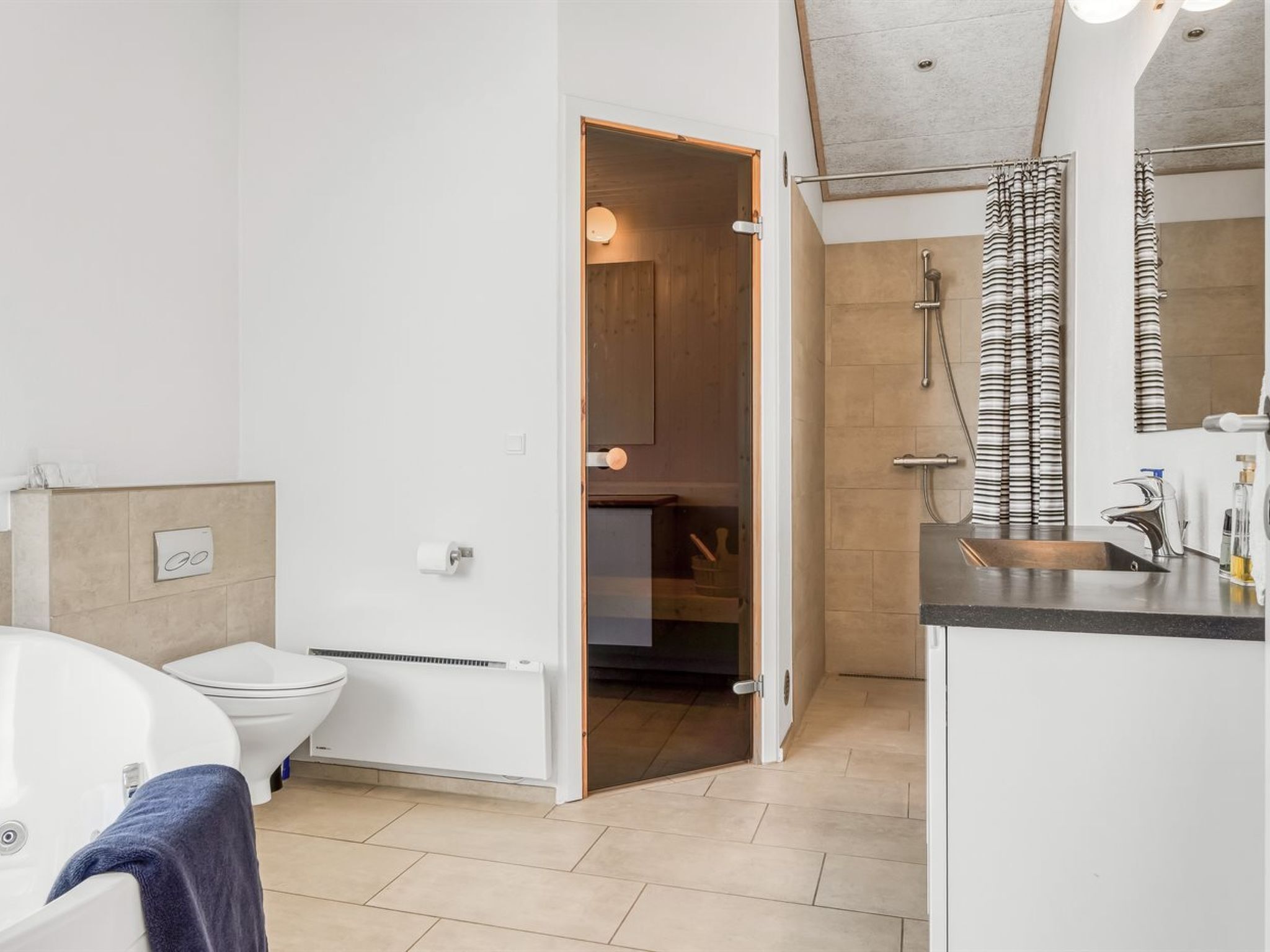 Une salle de bain moderne équipée d’une baignoire, de toilettes et d’un espace douche.