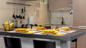 Une cuisine moderne dotée d’un îlot central, d’ustensiles suspendus et d’un dosseret carrelé.