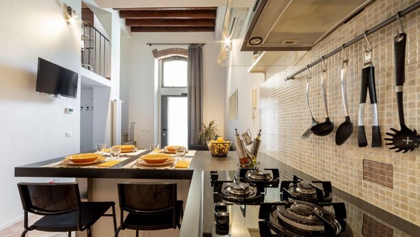 Une cuisine moderne dotée d’un îlot central, de chaises noires et d’une table à manger pour quatre personnes.