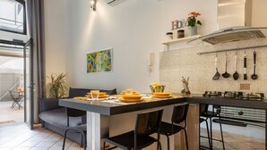 Une cuisine moderne avec un coin repas, comprenant un îlot de cuisine, des tabourets de bar et un canapé gris.