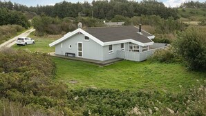 Une maison de plain-pied avec un toit en pente, une cour clôturée et une allée gravillonnée.