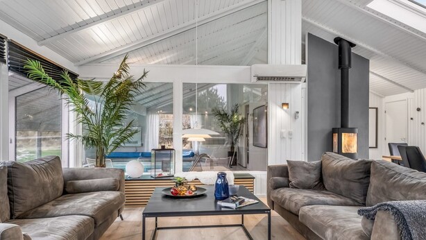 Ein großzügiger Wohnbereich im modernen Stil mit Ledersofas, einem Glastisch und einem großen Fenster mit Blick auf einen Pool.