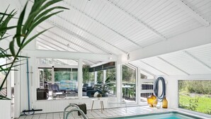 Ein Poolbereich mit freiem Blick auf den Pool, eine Sitzgelegenheit mit Stühlen und Tisch sowie ein großes Fenster mit Ausblick ins Freie.
