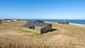 A coastal property with multiple small buildings, a grassy field, and a view of the sea.
