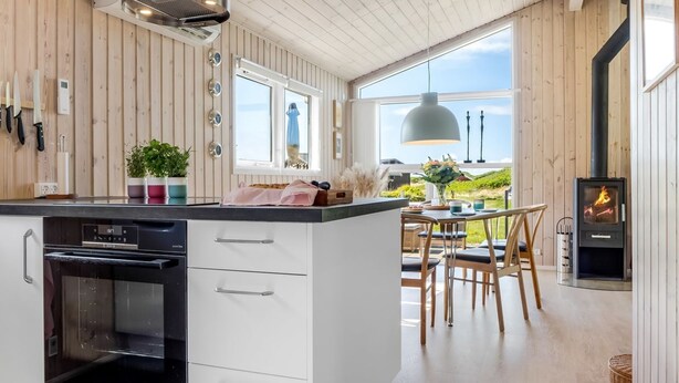 Una cocina moderna con horno empotrado, una zona de comedor con mesa y sillas, y un estufa de leña.