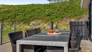 Un patio al aire libre con una mesa y sillas, una botella de champán y un cuenco con fresas.