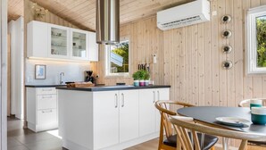 Una cocina moderna con armarios blancos, una isla central y un comedor con sillas de madera.