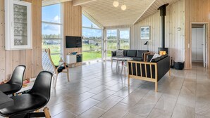 A spacious living area with a large window, a fireplace, a sofa, and a TV.