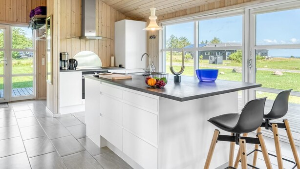 A modern kitchen with a large island, white cabinetry, and a view of the outdoors.
