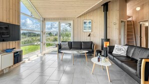 A modern interior with a wooden ceiling, a black leather sofa, a white coffee table, and a fireplace.
