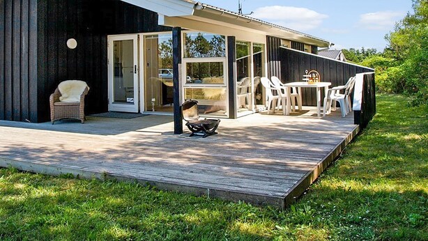 Una casa moderna con una terraza, un espacio de estar al aire libre cubierto y un amplio ventanal corredero.