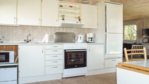 Una cocina moderna con armarios blancos, horno empotrado, cafetera y microondas.