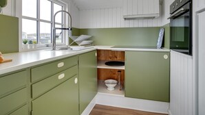 A compact kitchen with a window, green cabinets, a sink, and a microwave. - "Adina" - 50m from the sea by Interhome (Hjørring)