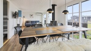 A modern dining area with a wooden table, black chairs, and a white furry rug. - "Adina" - 50m from the sea by Interhome (Hjørring)